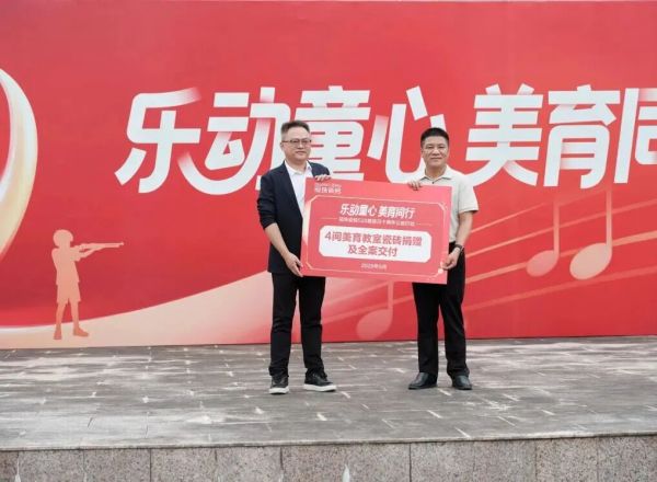 广州市增城区高滩小学校长宋志龙（右）与新明珠集团副总经理、冠珠瓷砖品牌总经理潘瀚（左）上台进行公益捐赠仪式